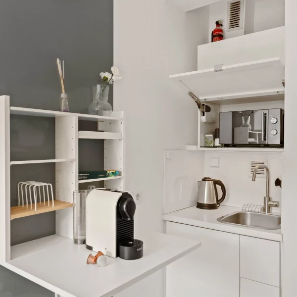 Kompakte Kitchenette mit Kaffeemaschine, Spüle und Mikrowelle im Cozy Cologne Rentals Apartment am Neumarkt in Köln.
